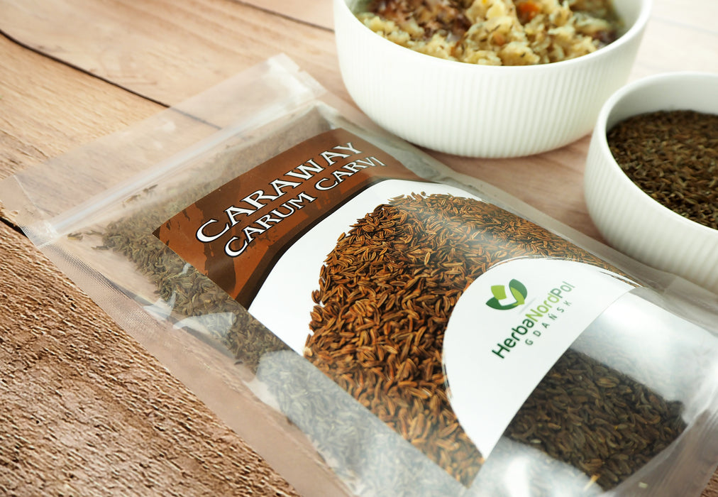 Das Bild zeigt ein ansprechendes Produktarrangement mit einer Packung Kümmelsamen (Carum carvi) von HerbaNordPol im Vordergrund. Hinter der Packung befindet sich ein weißer Teller mit einer appetitlichen Zubereitung aus Kohl und gestreuten Kümmelsamen, was die Verwendungsmöglichkeiten des Produkts illustriert.