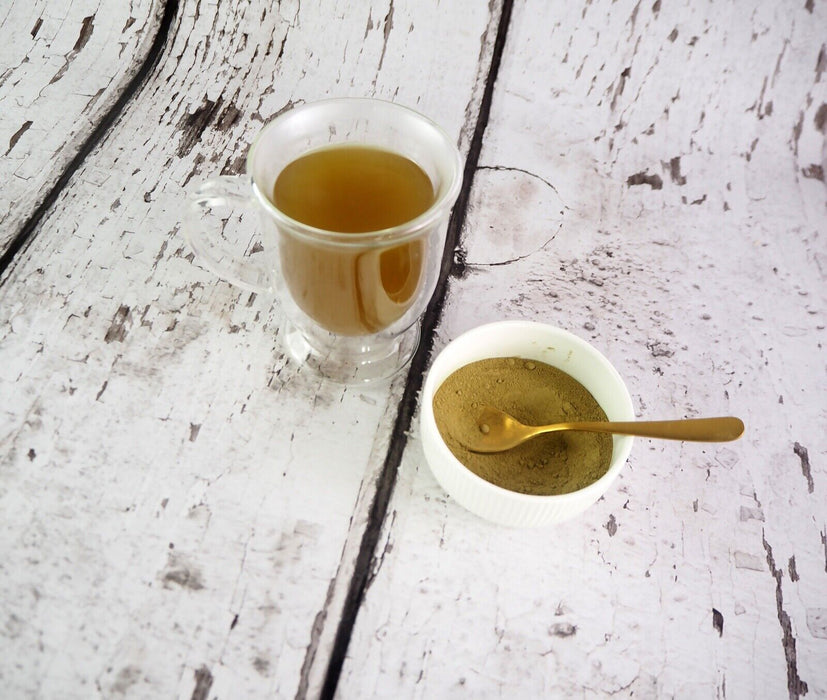 Transparente Tasse mit aufgebrühtem Bio Yerba Mate und Mate-Pulver in einer Keramikschale.